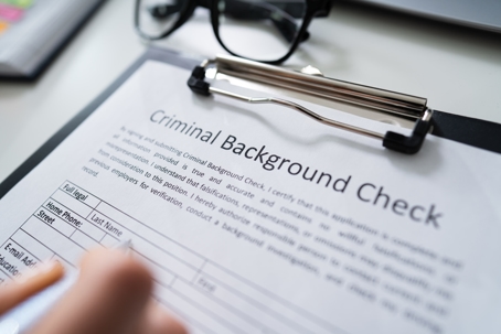 A close-up of a person filling out a criminal background check form. | Matthew Penick Law